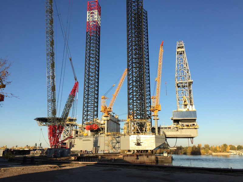 EDC Mercury jack-up under construction with its legs, drilling derrick and yard cranes visible